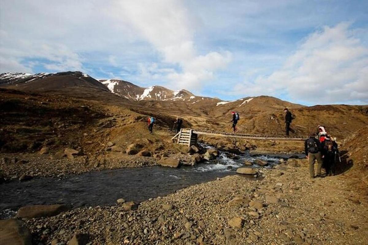 hópur fólks sem gengur á brú yfir fjallslæk