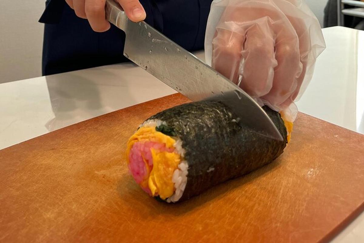 osoba s nožem krájející kus sushi