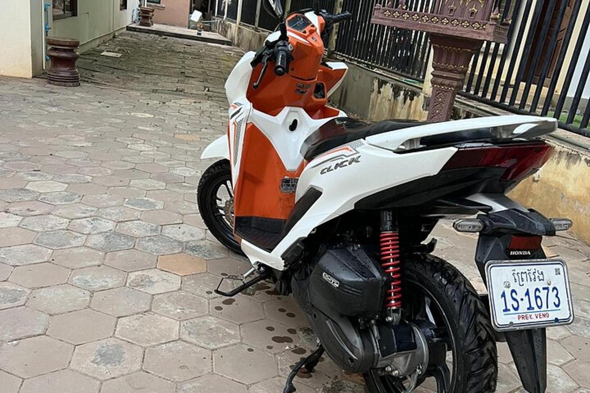une moto orange et blanche garée sur un trottoir