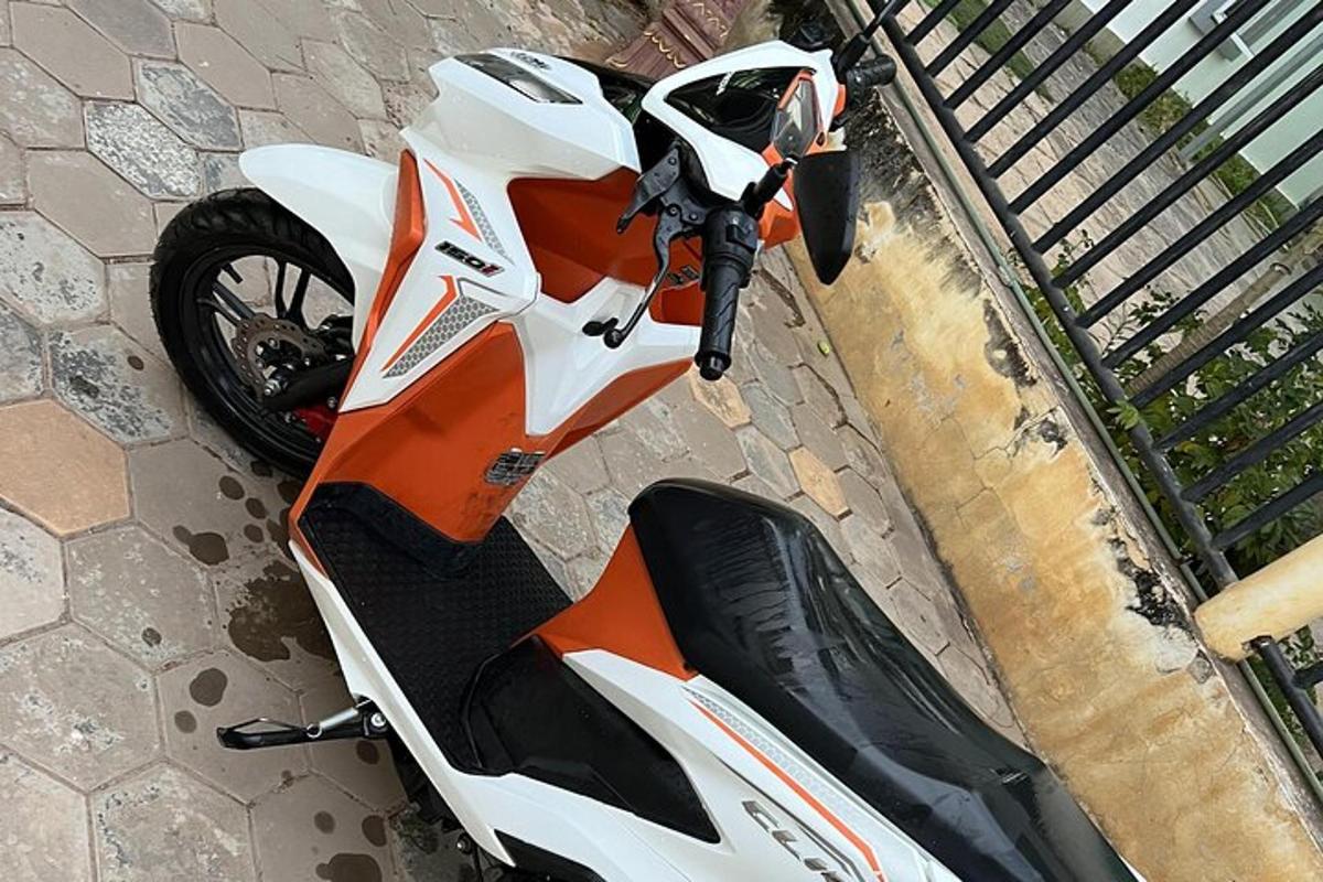 an orange and white motorcycle parked on a sidewalk