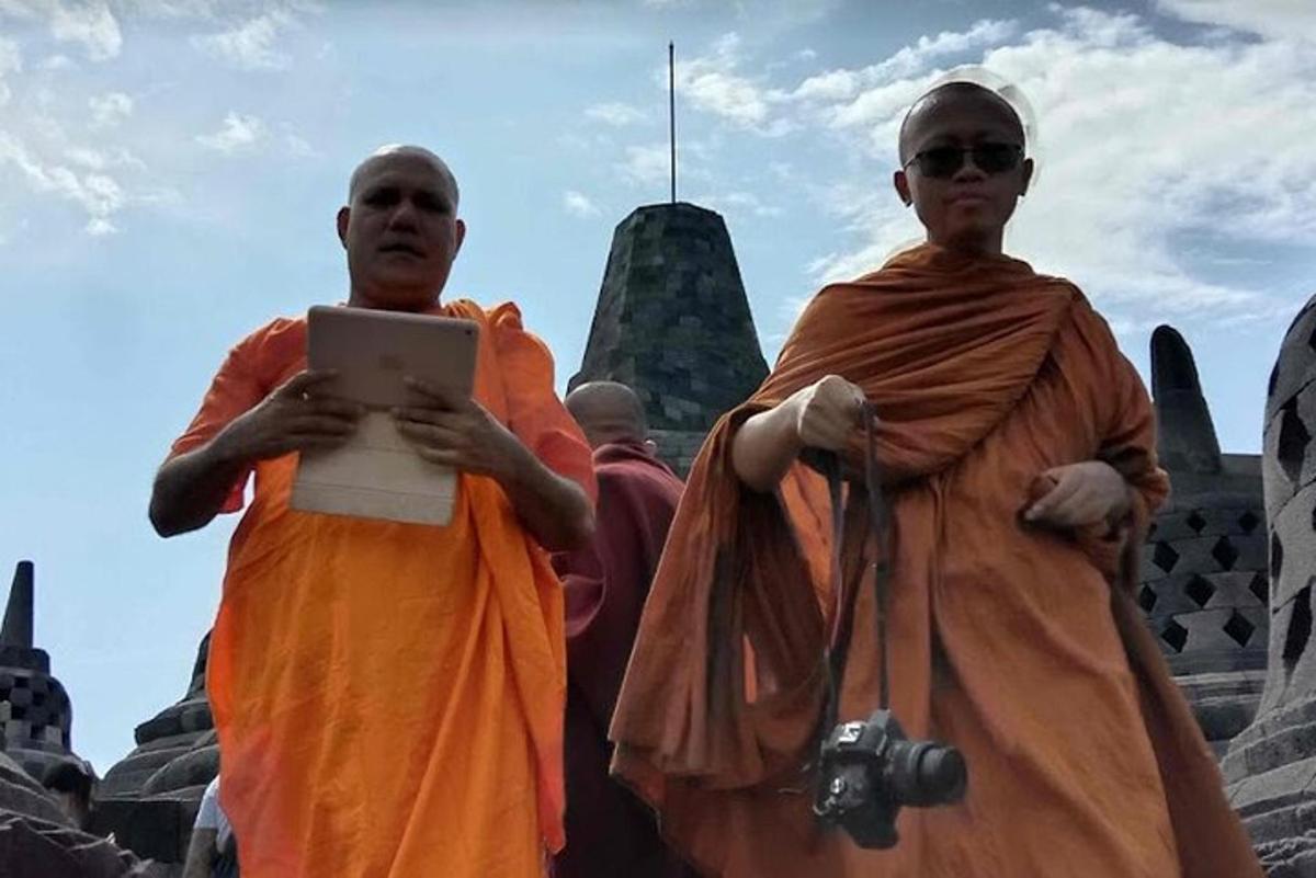 dois homens em pé em frente a uma estátua com uma placa