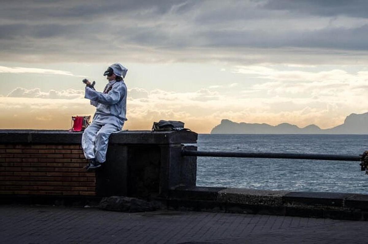 Un hombre sentado en un muro tomando una fotografía del océano.