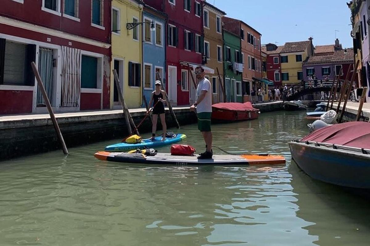 dva lidé stojí na paddleboardech v kanálu