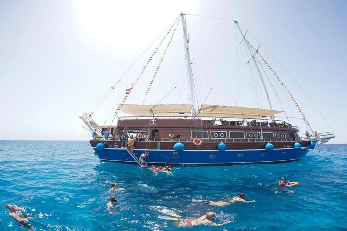 pessoas nadando na água em frente a um barco