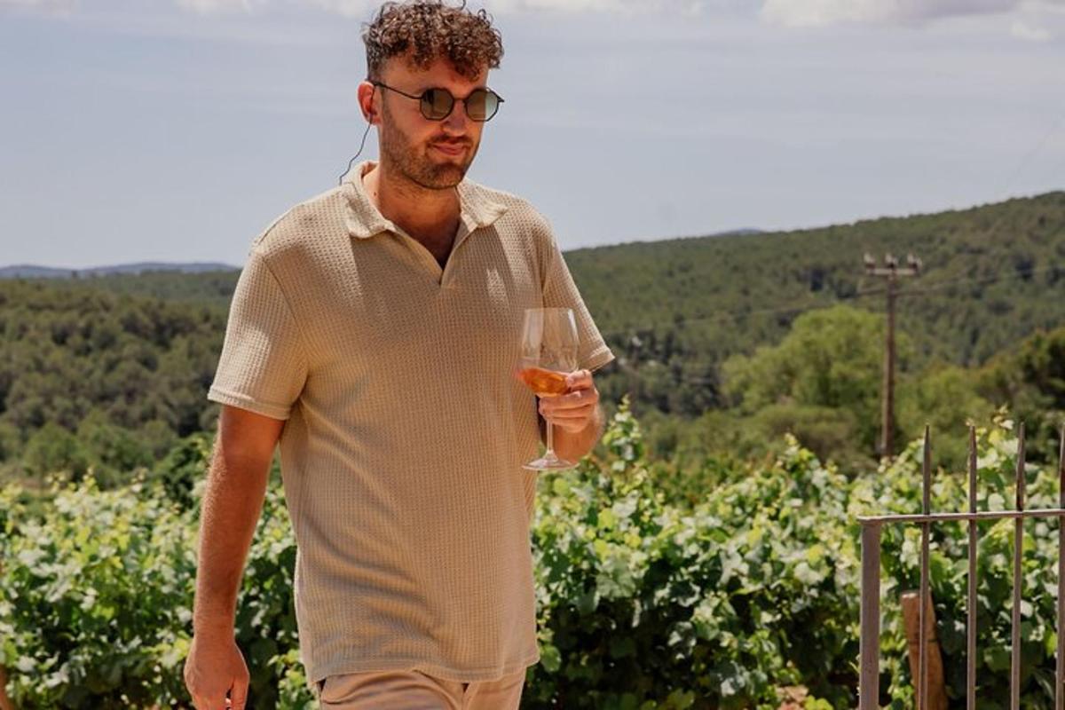 muž držící sklenici vína ve vinici