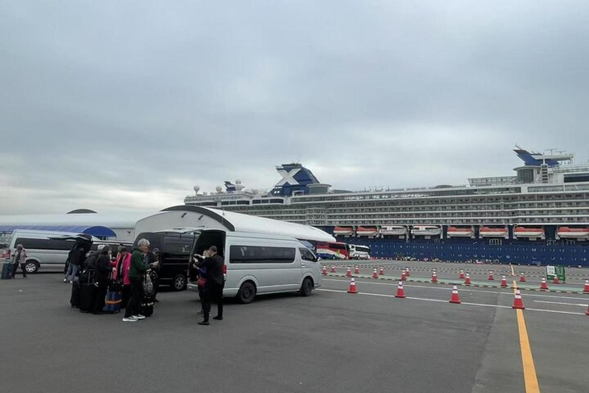 eine Gruppe von Menschen steht neben einem Lieferwagen und einem Kreuzfahrtschiff