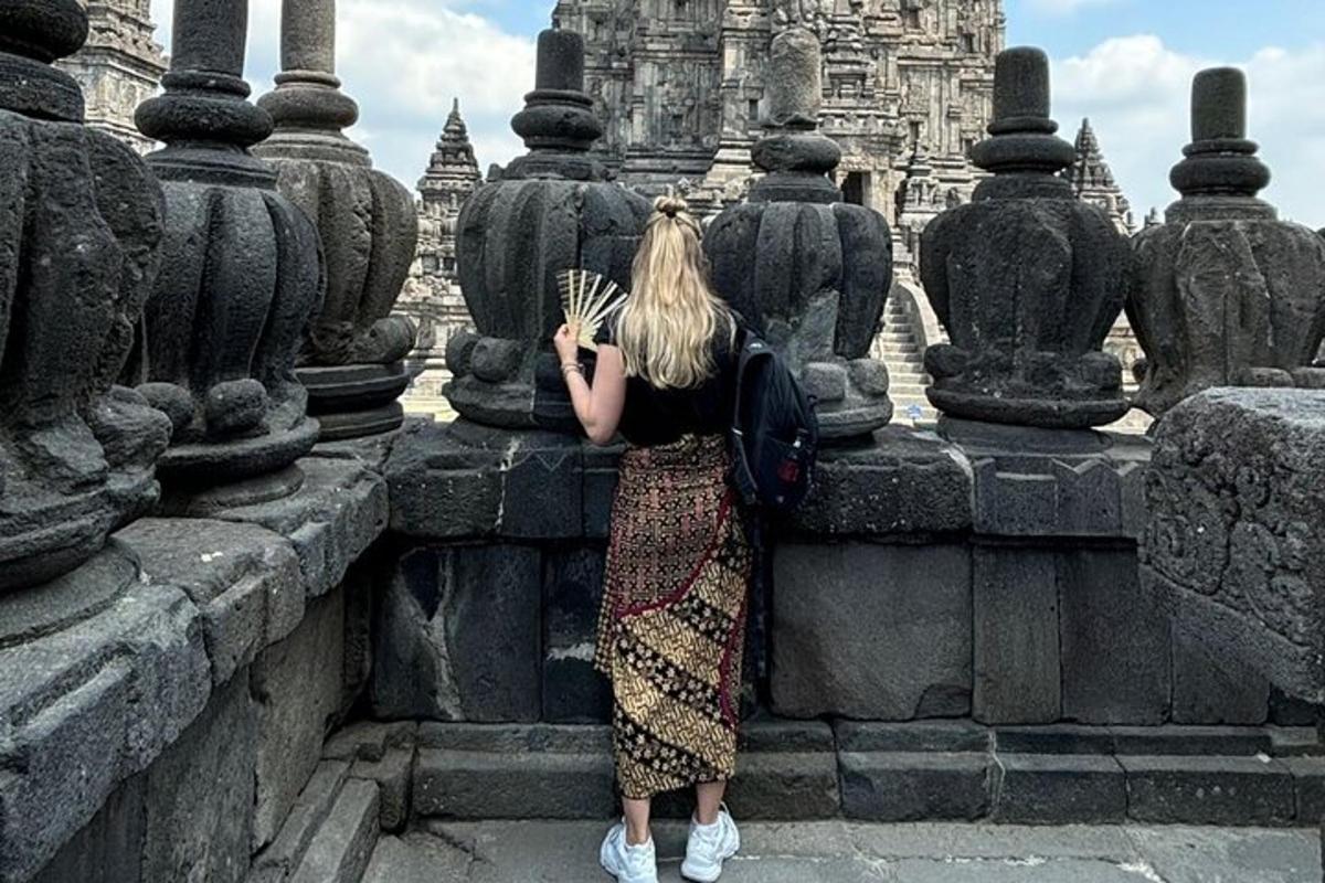 một người phụ nữ đứng dựa vào tường cầm một chiếc quạt