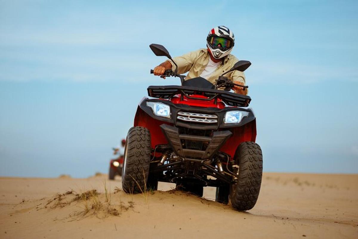 seseorang yang menunggang basikal quad di padang pasir