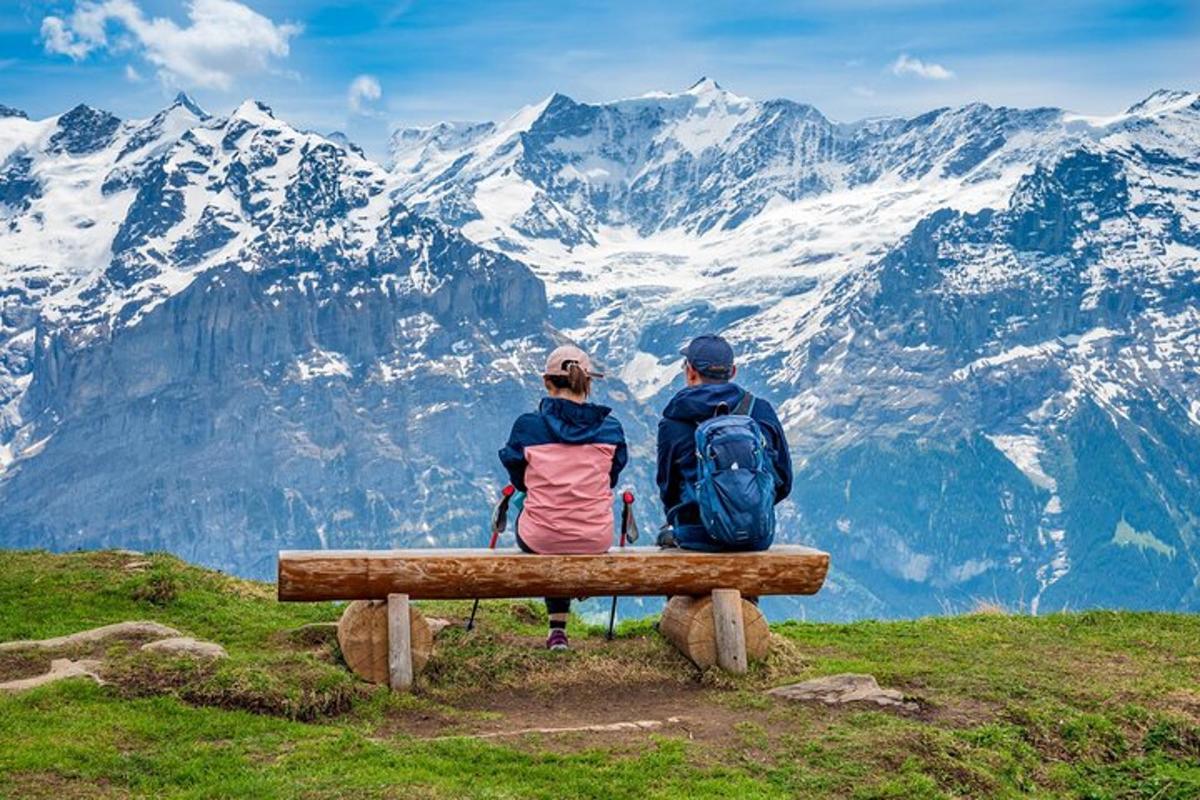 zwei Personen sitzen auf einer Bank auf einem Berggipfel