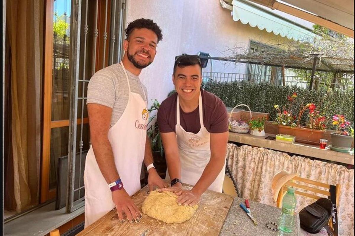 due uomini sono in piedi accanto a un tavolo e preparano il cibo