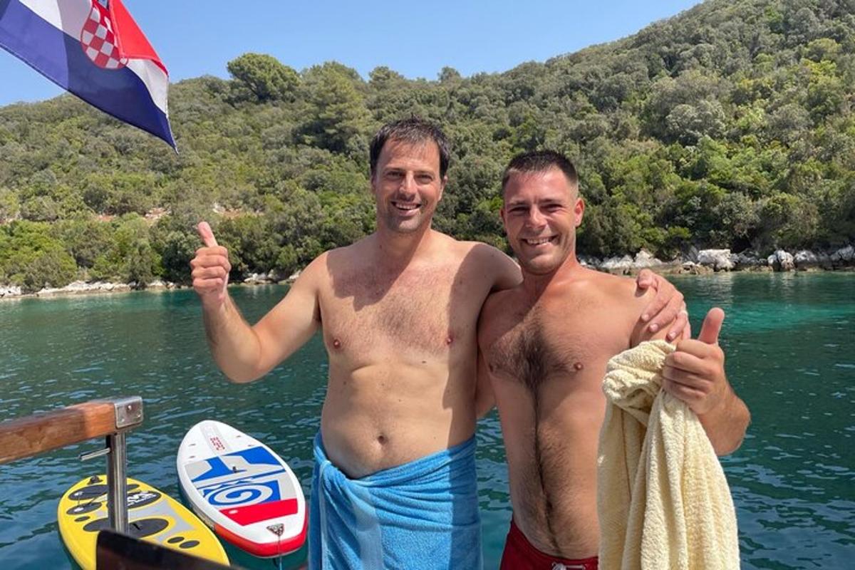 dois homens fazendo sinal de positivo em um barco na água