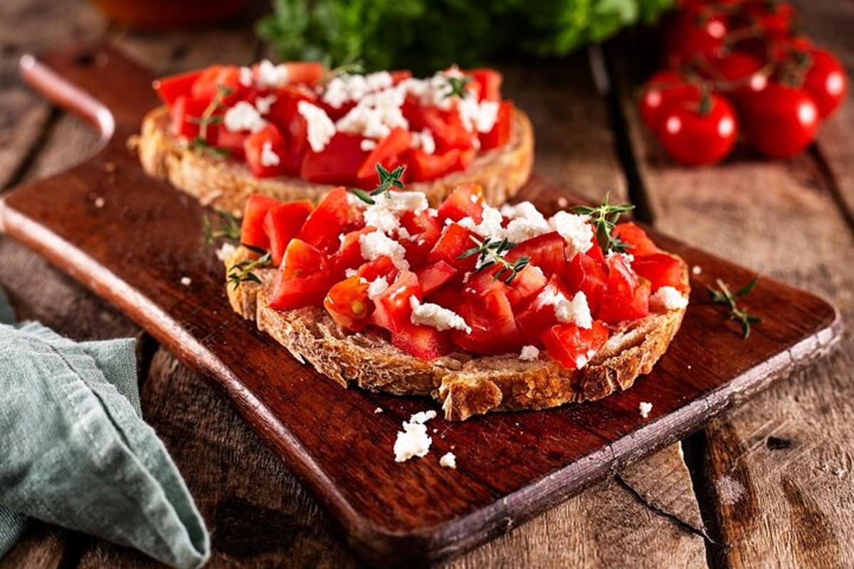 two slices of bread with tomatoes on a wooden cutting board