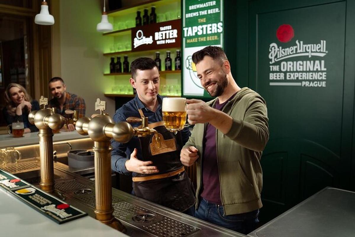 two men standing at a bar with a mug of beer