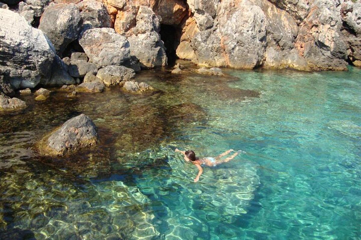 a person swimming in a body of water with rocks
