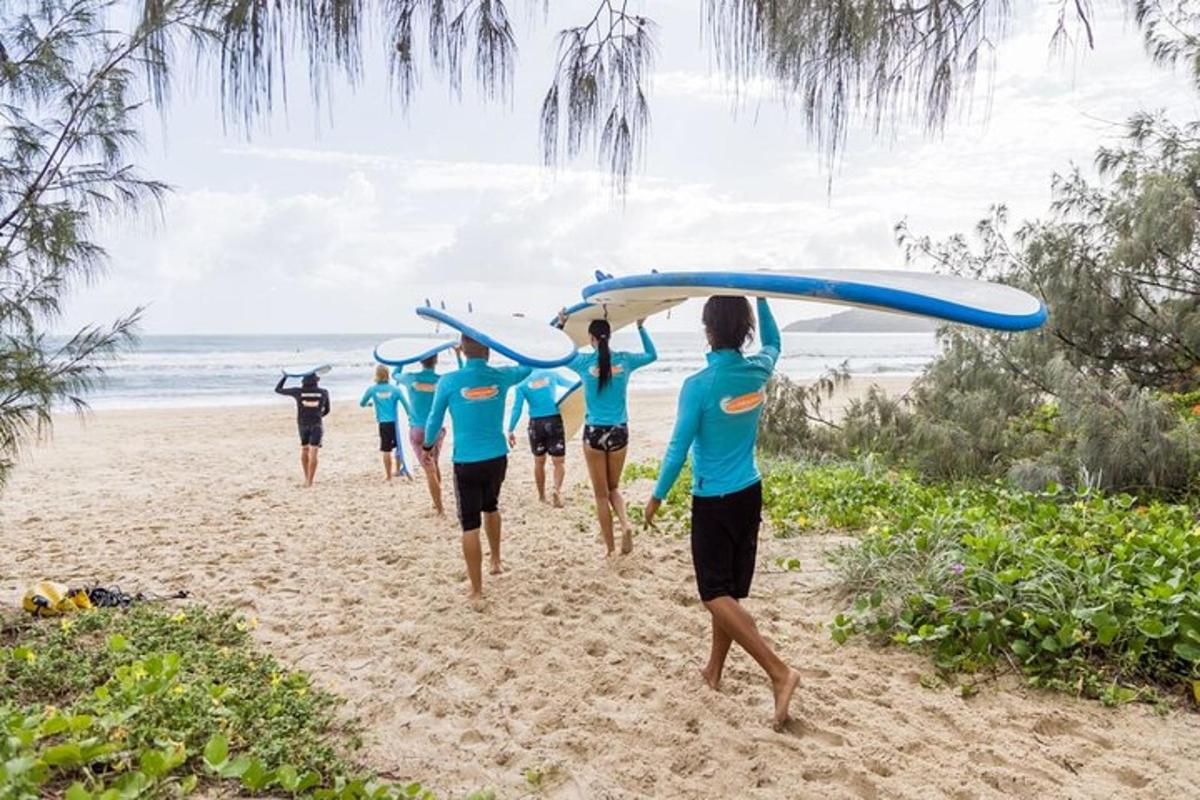 a group of people carrying surfboards on a beach