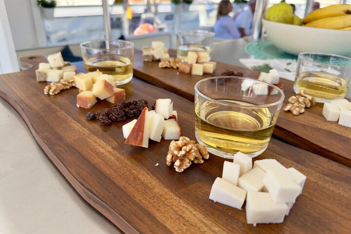 papan pemotong kayu dengan keju dan gelas alkohol