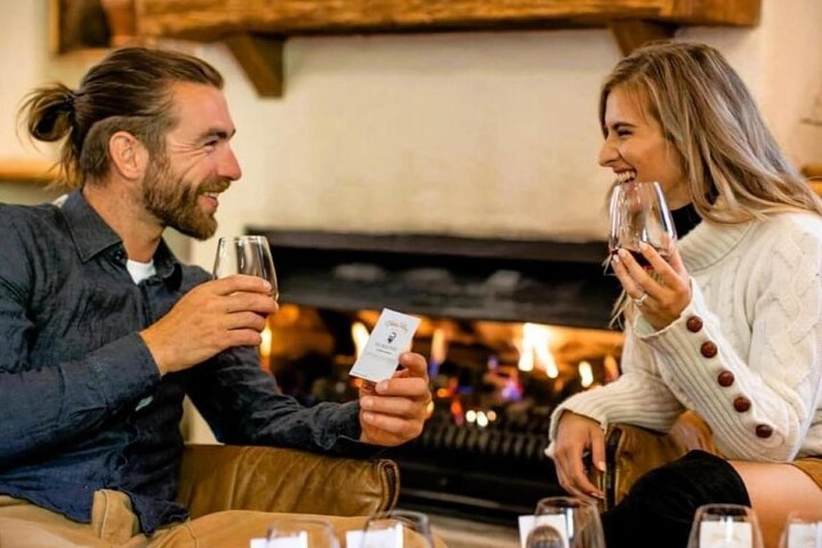 a man and woman drinking wine in front of a fireplace