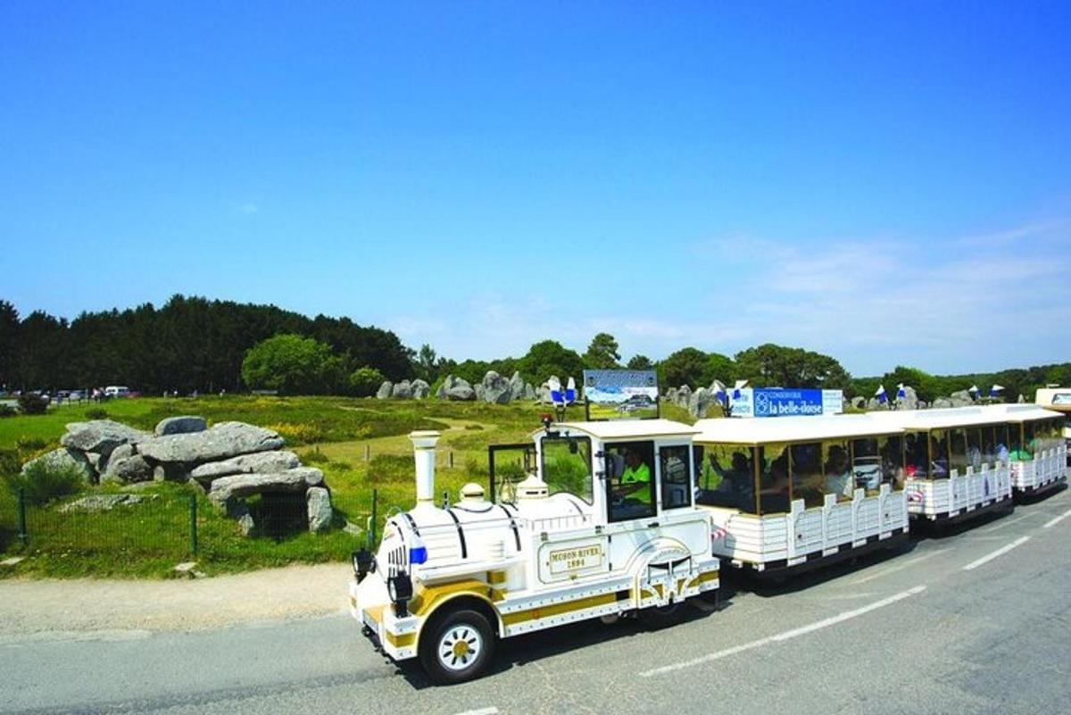 a small bus driving down the road near a field