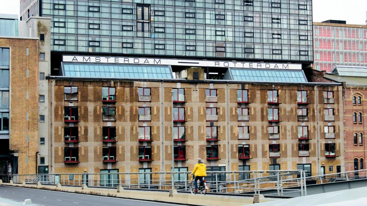 особа која стоји на мосту испред зграде