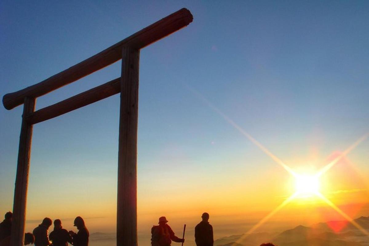 un grup de persones dretes al cim d'una muntanya amb la posta de sol