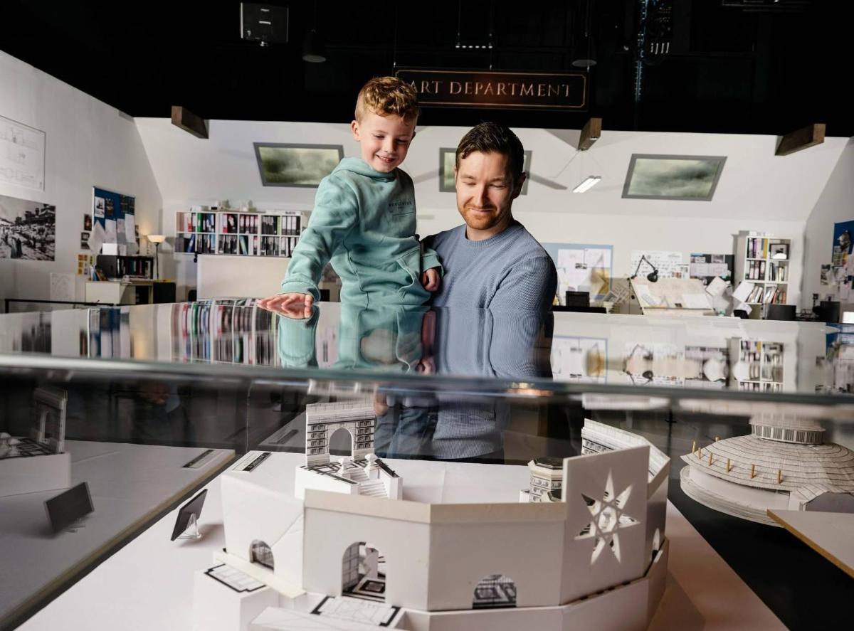 a man holding a child in a display case in a store
