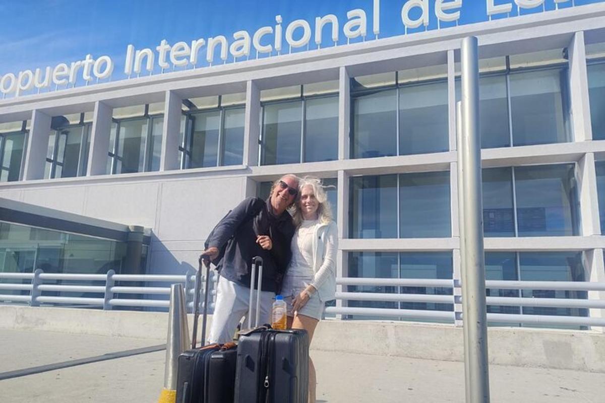 um homem e uma mulher em pé em frente a um aeroporto com bagagem