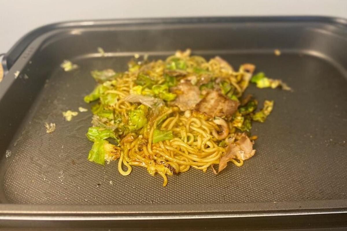 Una comida de fideos y brócoli en una sartén.