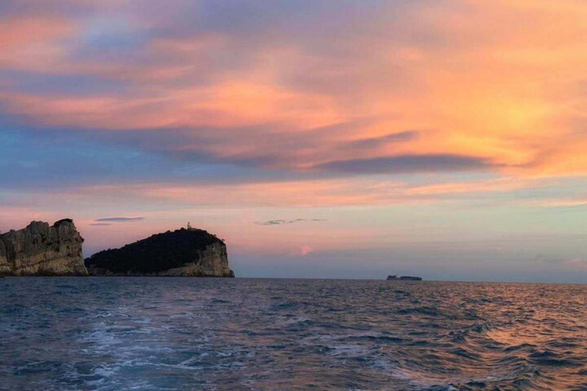 um pôr do sol sobre o oceano com uma pequena ilha