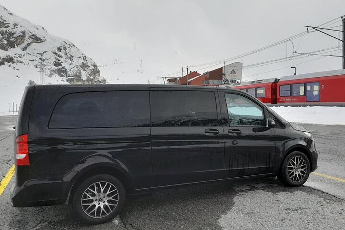 uma van preta estacionada em um estacionamento com um trem