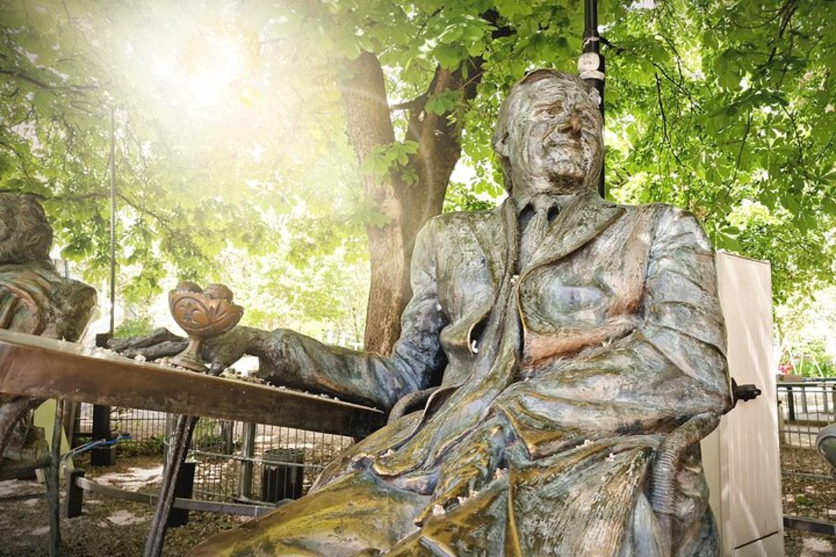 eine Statue eines Mannes, der auf einer Bank sitzt