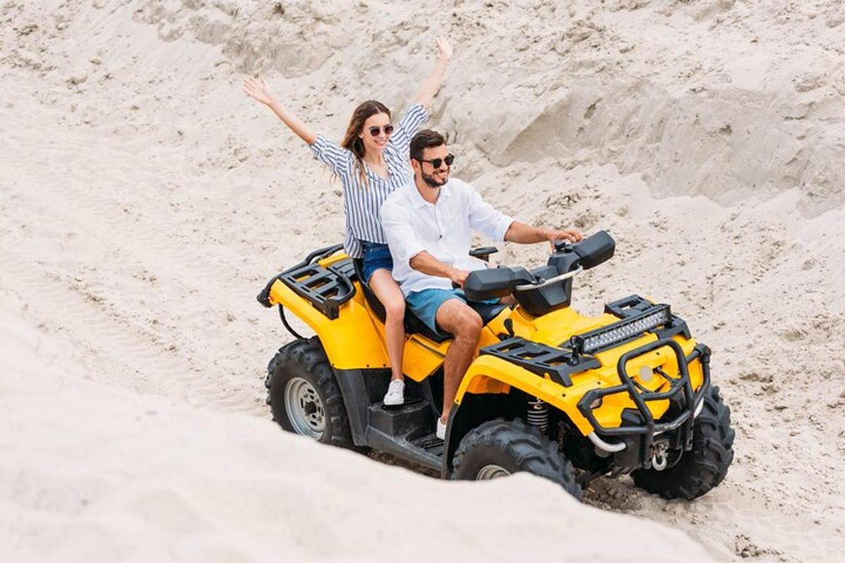 um homem e uma mulher andando em um quadriciclo na areia