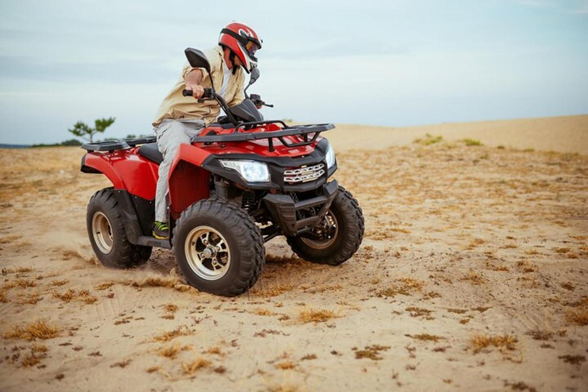 seseorang yang menunggang atv merah di padang pasir