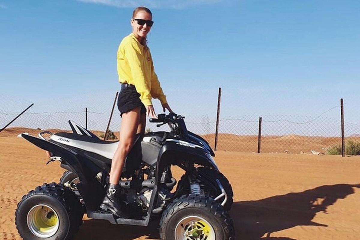 um homem em pé em um caminhão com rodas no deserto