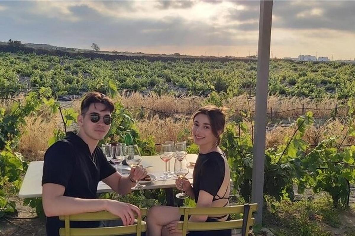 Dos personas sentadas en una mesa con copas de vino.
