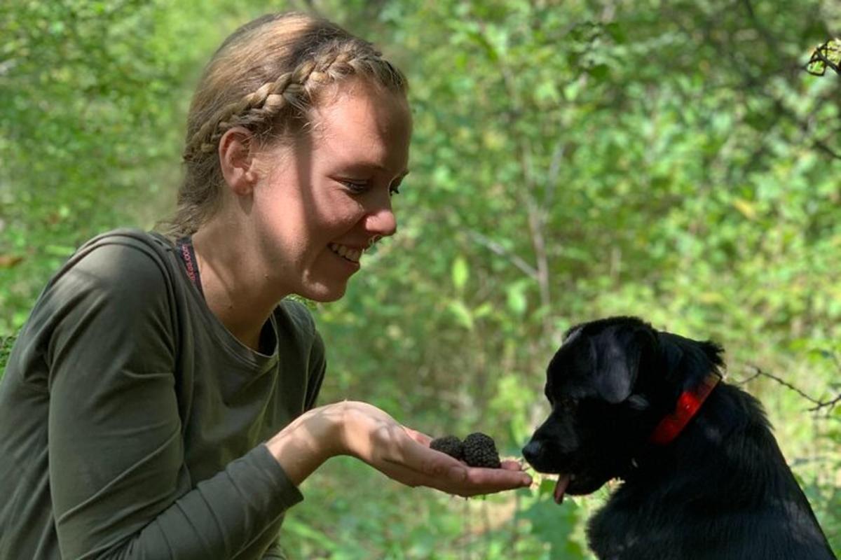žena krmí černého psa kusem jídla