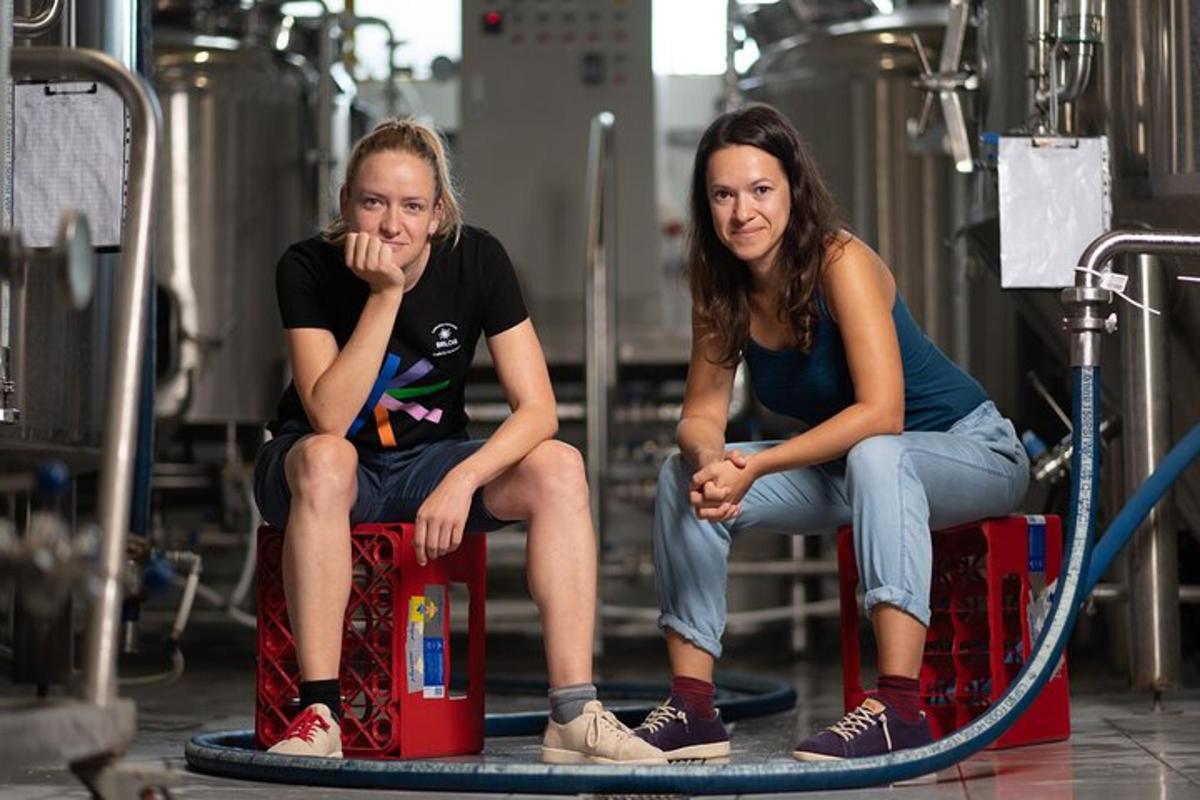 Divas sievietes sēž uz koferiem rūpnīcā