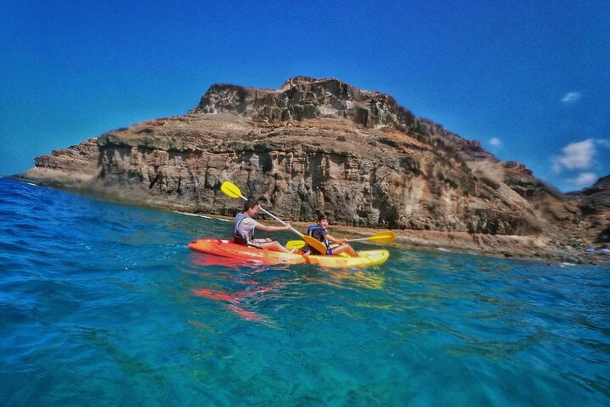 dua orang menaiki kayak di dalam air berhampiran gunung