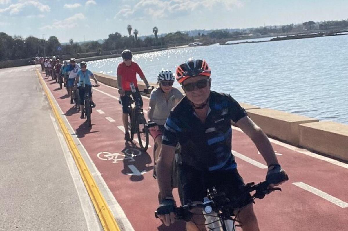 un grup de persones anant en bicicleta per una carretera vora l'aigua