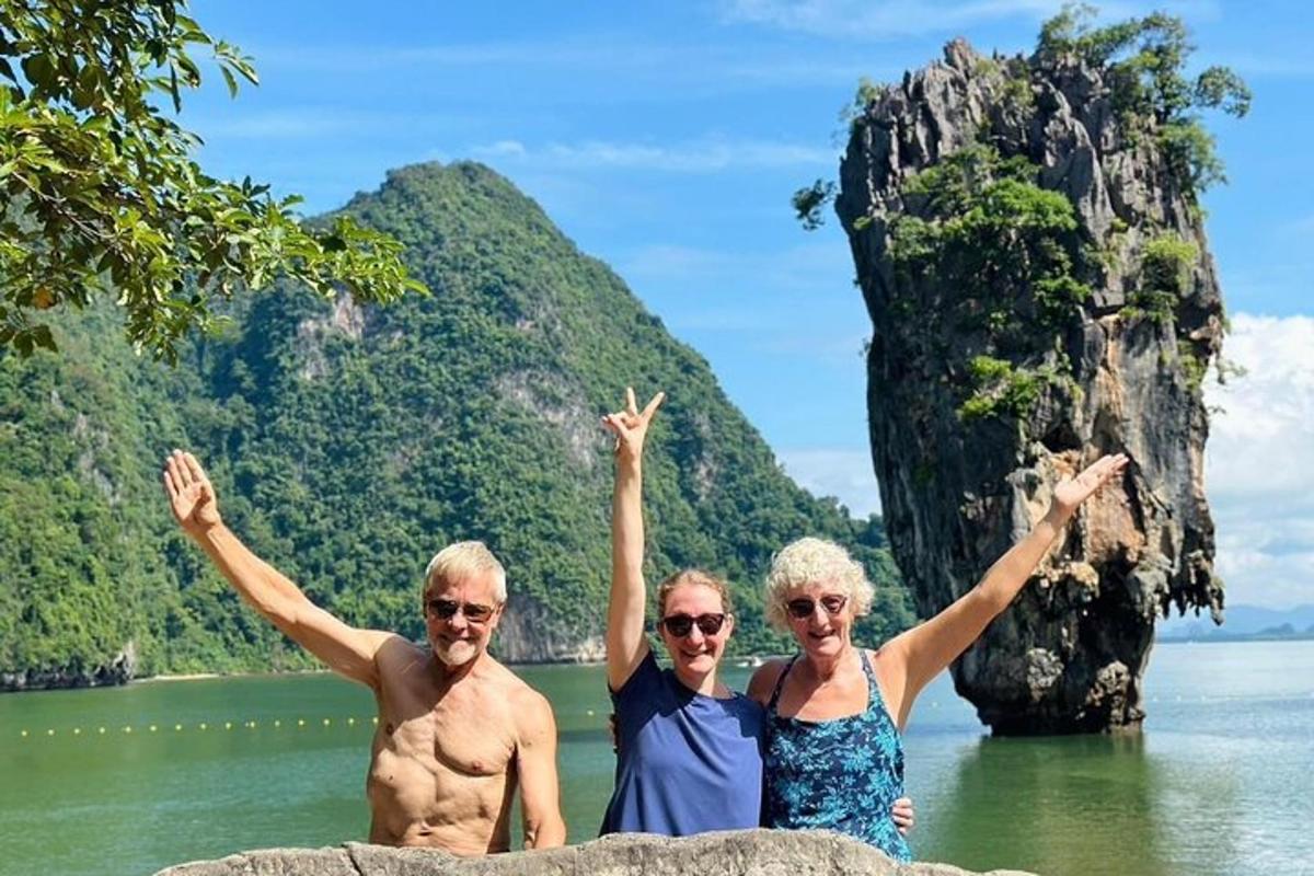 three people standing on a rock in the water with their arms up