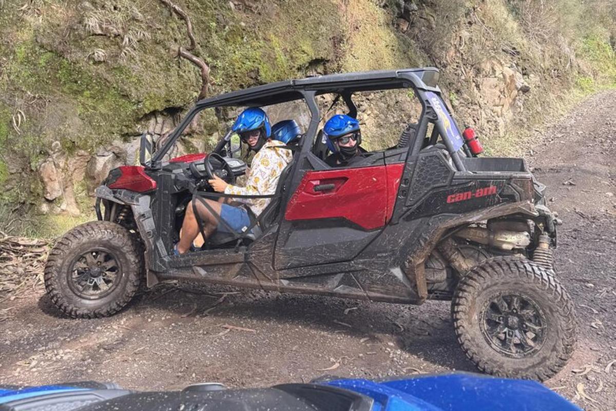 tatlong tao na nakasakay sa isang four wheeler sa isang maruming kalsada
