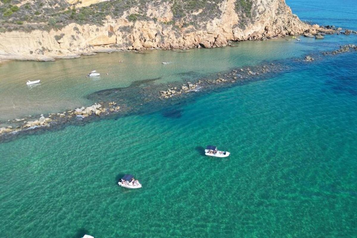 due barche in acqua accanto a un'isola rocciosa