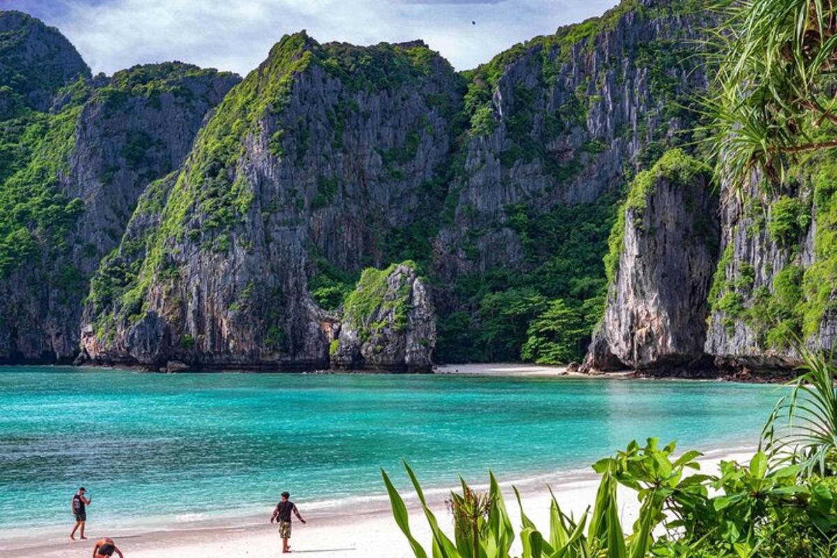 persone che camminano sulla spiaggia di fronte a una spiaggia con scogliere