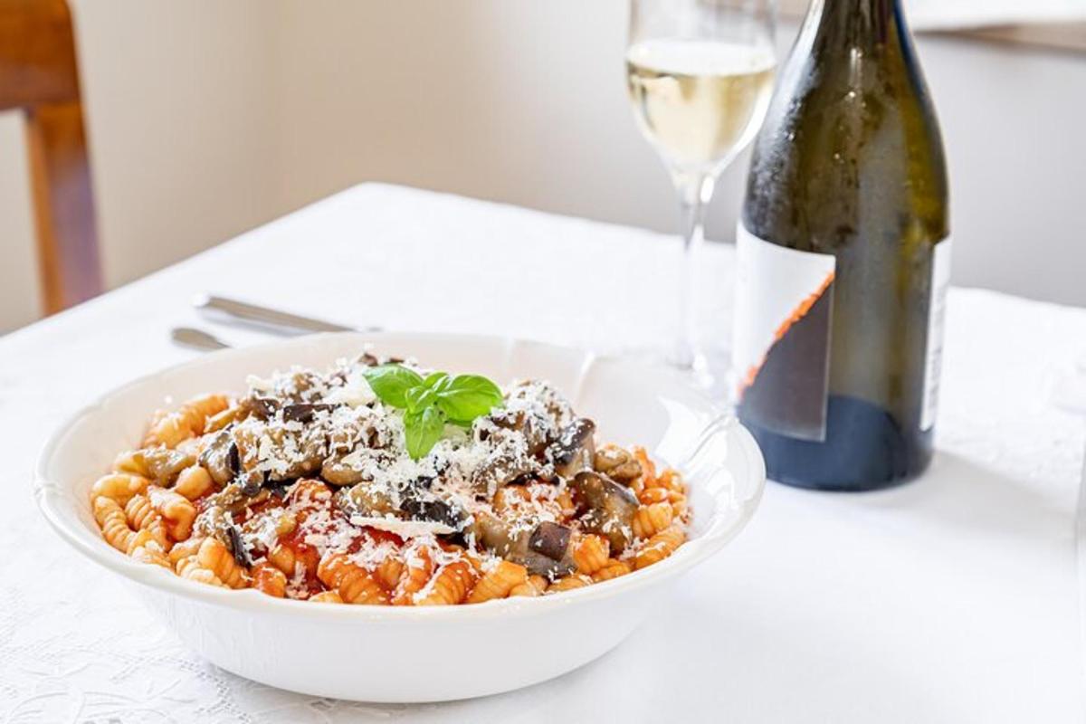Un plato de pasta junto a una botella de vino