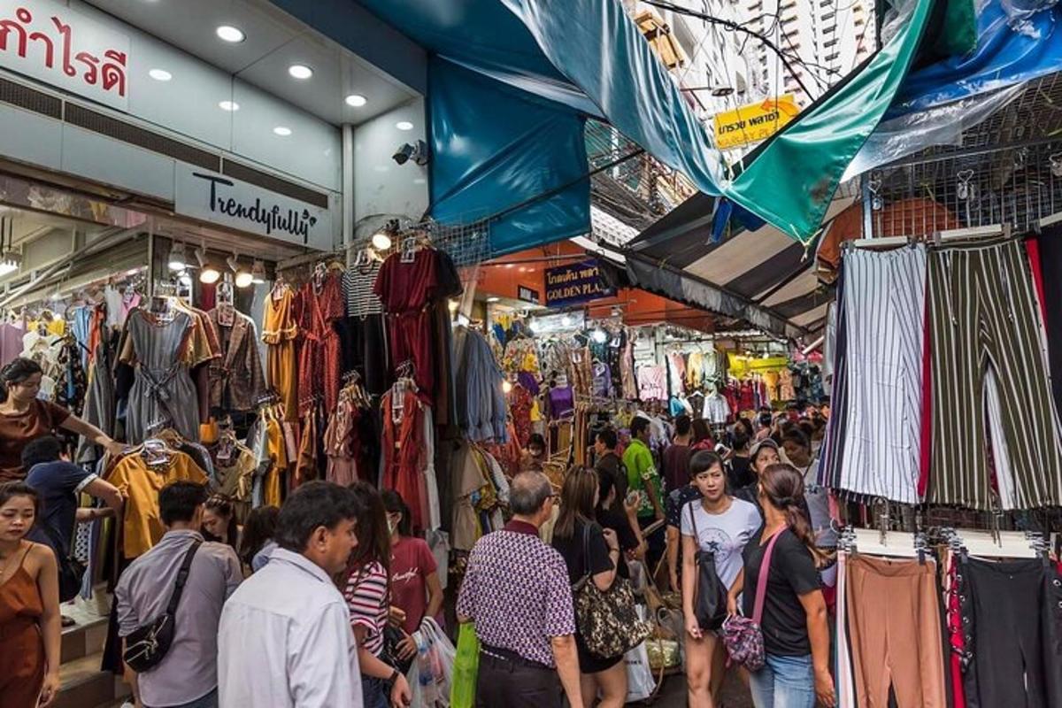 una folla di persone che camminano in un mercato con i vestiti