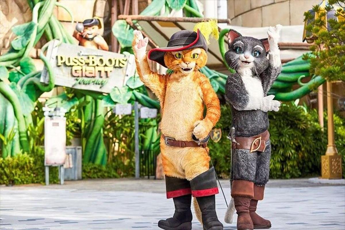 two mascots dressed in costumes standing in front of a disneys exhibit