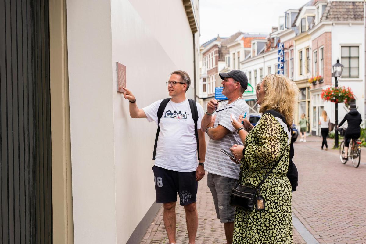 Dos hombres y una mujer de pie junto a una pared
