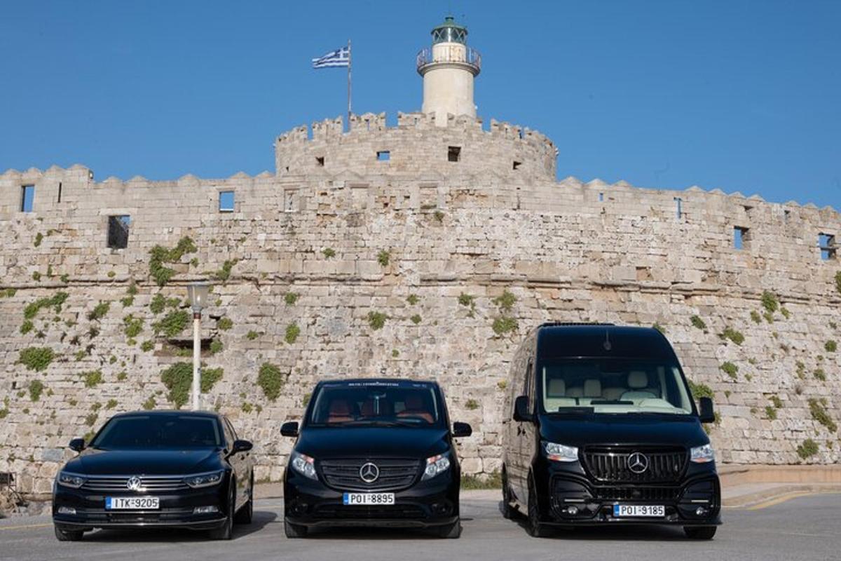 two vehicles parked in front of a stone wall with a lighthouse