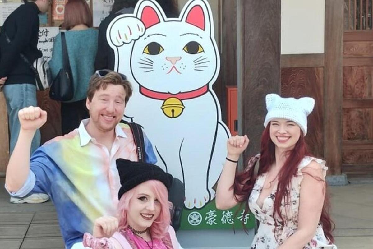 un gruppo di persone in posa davanti a un cartello raffigurante un gatto