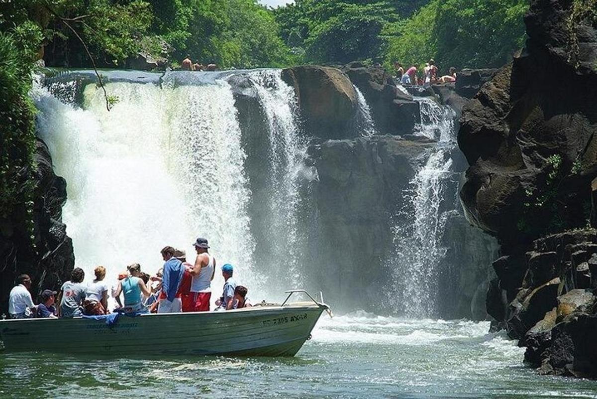 eine Gruppe von Menschen auf einem Boot vor einem Wasserfall
