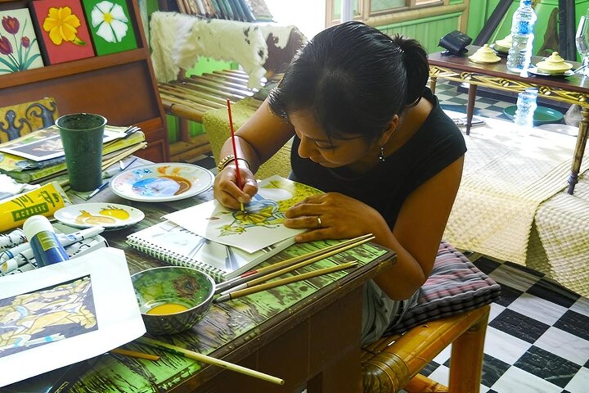 Una mujer sentada en una mesa pintando un plato de comida.